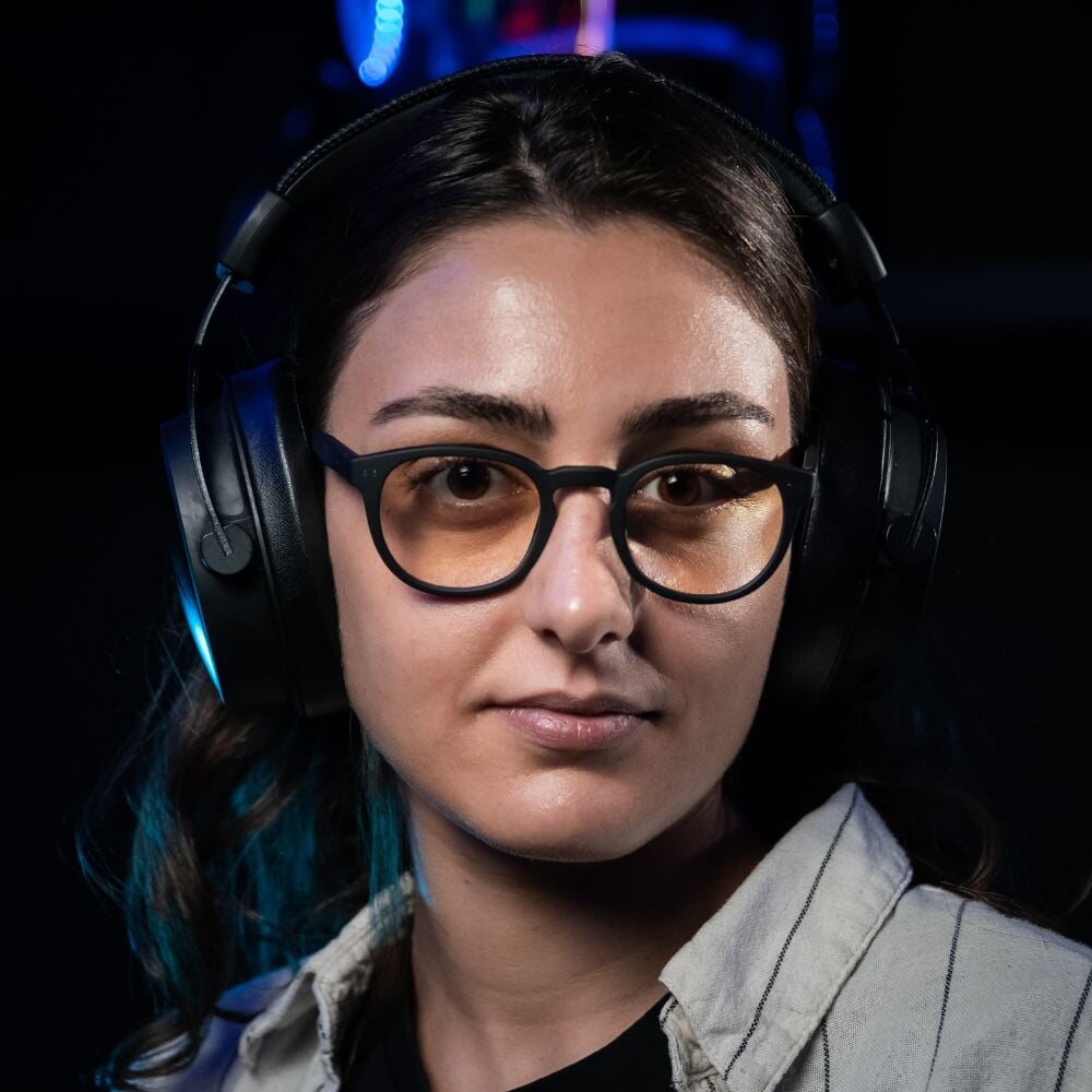 Notre modèle Hélène porte les lunettes gamer urban revolution avec verre ambré et un casque audio sur fond noir de profil
