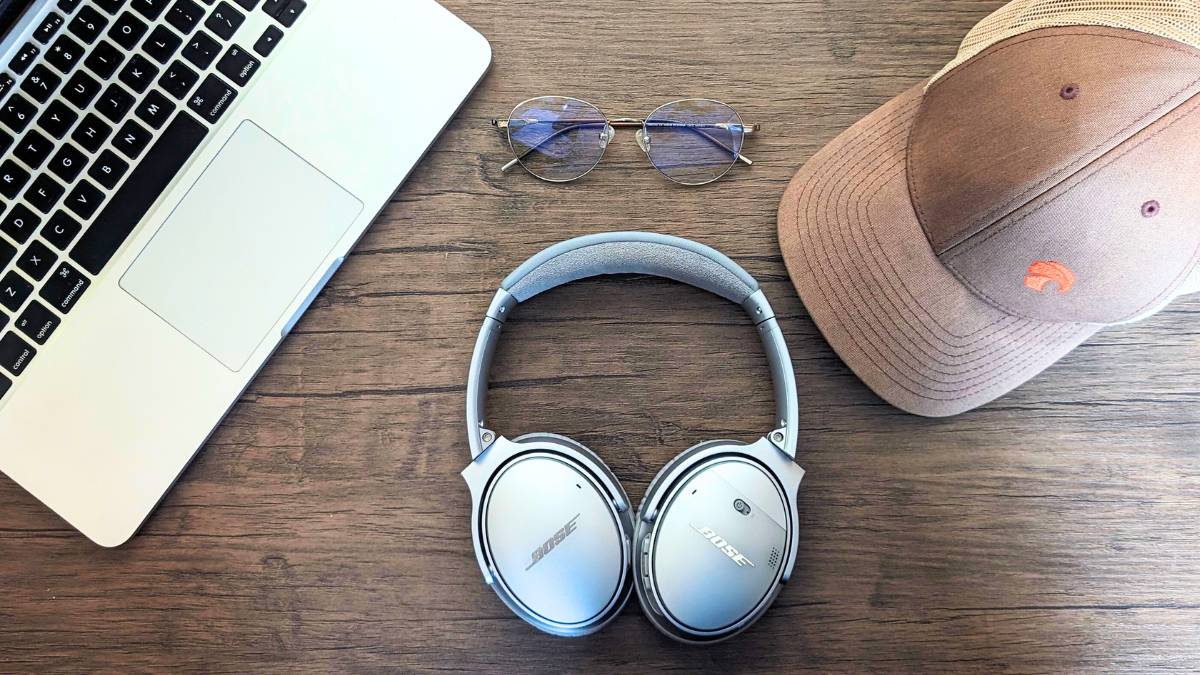 les écouteurs, un ordinateur portable, des lunettes horus x avec une casquette horus x sur la table