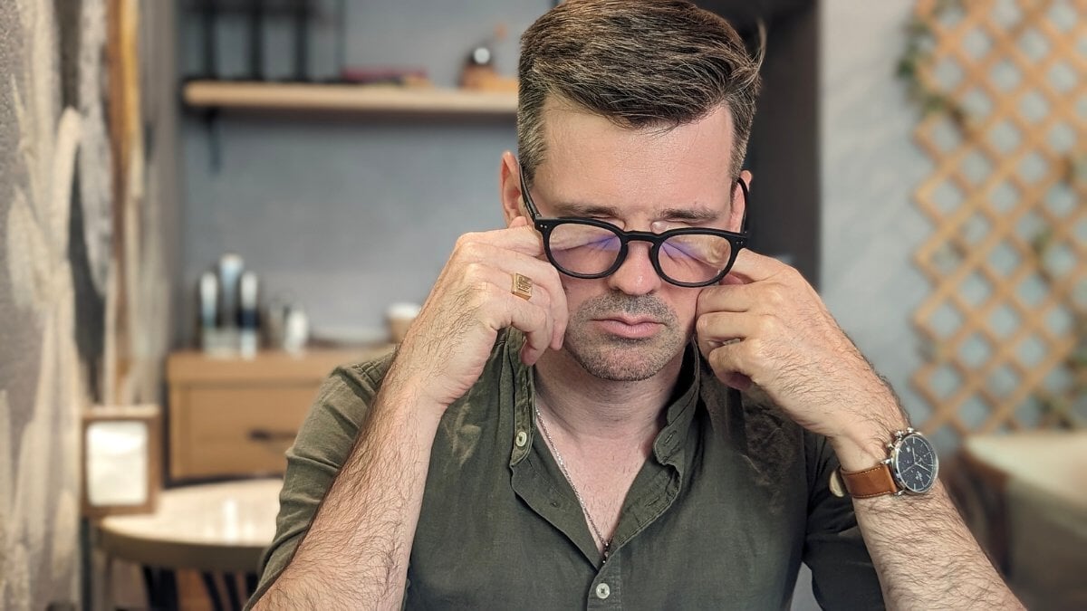 un homme se gratte les yeux devant l'ordinateur