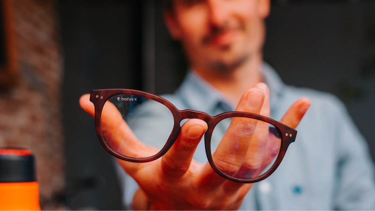 un jeune homme tenant des lunettes horus x