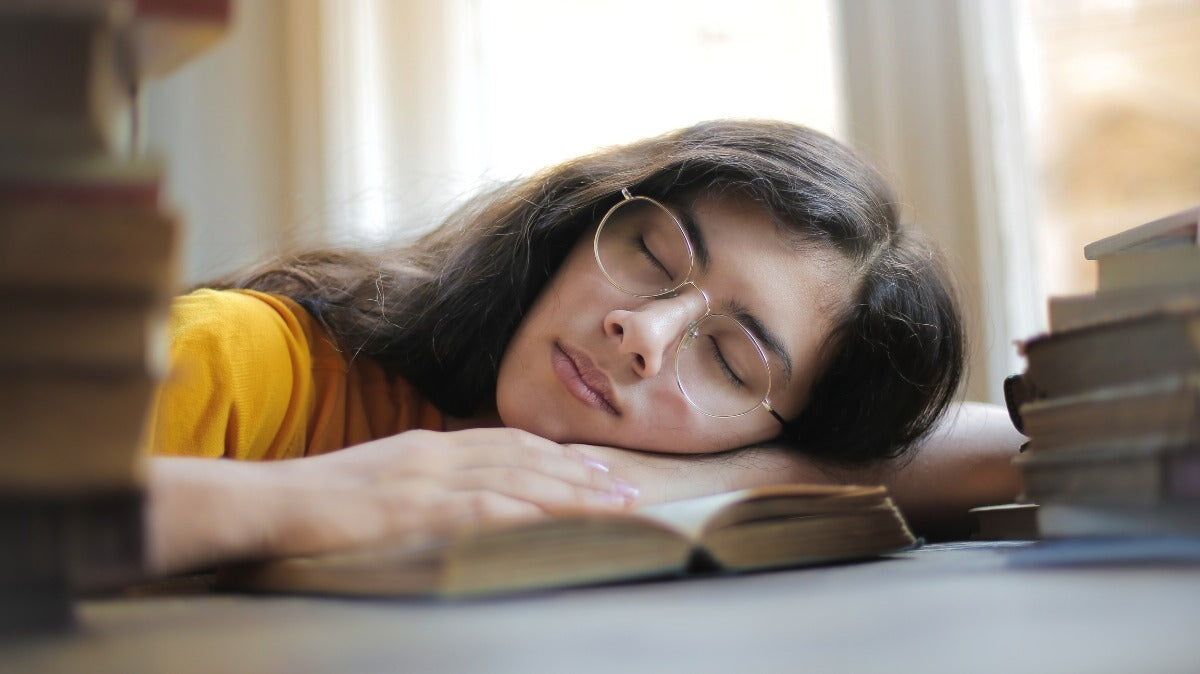 une femme portant des lunettes dormant sur un livre