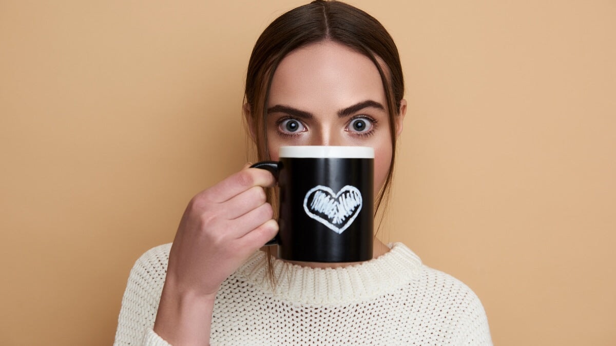 une jeune femme tenant une grande tasse devant son visage